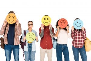 5 people holding a big circle in front of their face. Each circle has a different facial expression on it and is a different color.