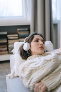 Person laying on a coach with headphones staring off to the side.