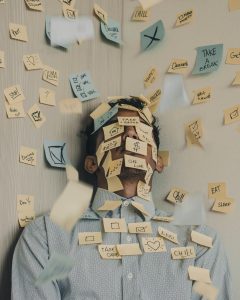Someone leaning back into a corner covered in sticky notes with various symbols written on them, like checklist, unchecked boxes, and notes.