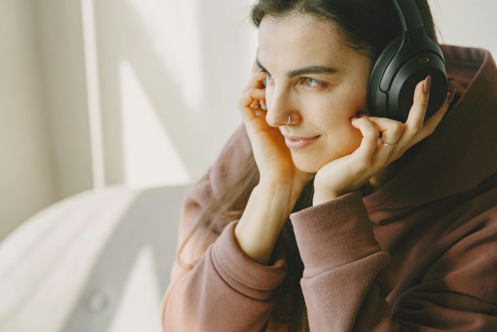 A person wearing noise cancelling headphones. Their hands are touching each side of the headphones. 